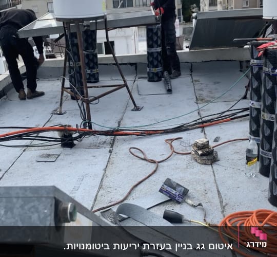 עובדים על גג עם יריעות איטום וכלי עבודה